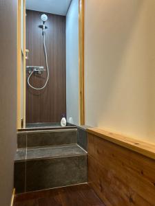 a shower in a bathroom with a wooden wall at Butter Hotel in Otari +26 photos