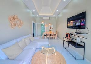 a living room with a white couch and a flat screen tv at Khunnapat Pool Villa Pranburi in Ban Huai Thalaeng Phan