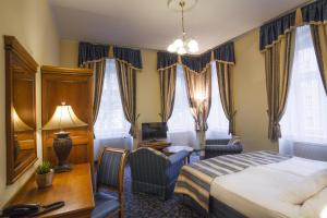 ein Hotelzimmer mit Bett, Schreibtisch und Fernseher in der Unterkunft Hotel Ontario in Karlsbad