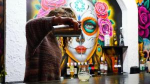 a woman standing at a bar pouring a drink at Butter Hotel in Otari