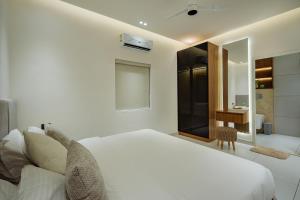 a bedroom with a white bed and a bathroom at Royale Suites - 3 BHK Serviced Apartment in Kadayirippu