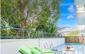 a swimming pool with green chaise lounge chairs on a fence at Villa Avanora by DanCenter in Arpora