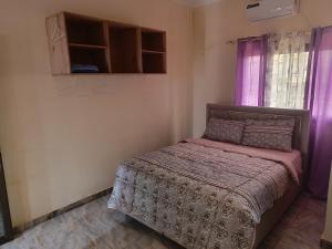 a bedroom with a bed and a window with purple curtains at Très Bel Appartement Moderne-1 Appartement Nuptial in Libreville