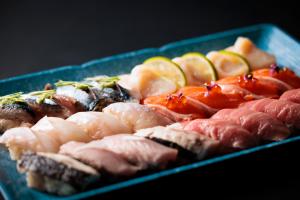 een blauwe bak gevuld met sushi en fruit bij the SHIHACHI 