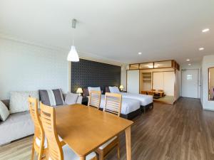 伊東市にあるAMBIENT 伊豆高原 コンドミニアムのベッドとダイニングテーブルが備わるホテルルームです。