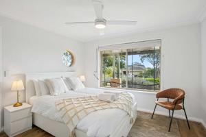 a white bedroom with a bed and a chair and a window at Seaview Escape Ocean Views & 500MBs Wifi in Perth