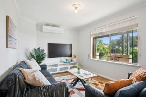 a living room with a couch and a tv at Seaview Escape Ocean Views & 500MBs Wifi in Perth