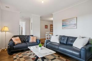 a living room with a black leather couch and a table at Seaview Escape Ocean Views & 500MBs Wifi in Perth +29 photos