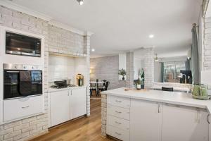 a kitchen with white cabinets and a brick wall at Seaview Escape Ocean Views & 500MBs Wifi in Perth