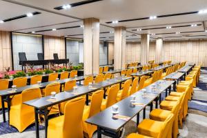 サマリンダにあるYello Hotel Samarindaのテーブルと黄色い椅子とピアノのある部屋