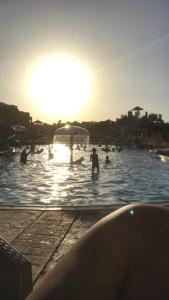 eine Gruppe von Menschen in einem Schwimmbad bei Sonnenuntergang in der Unterkunft قريه مرسيليا بلوباي السخنه --للعائلات فقط-Marseilia Blue Bay Ain Sokhna Village-- families only-- in Ain Suchna