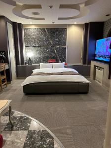a bedroom with a large bed and a flat screen tv at Hotel Sun tsuyama in Tuyama