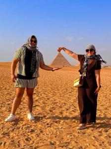 twee mensen staan op het strand met de piramides op de achtergrond bij Giza pyramids in Giza