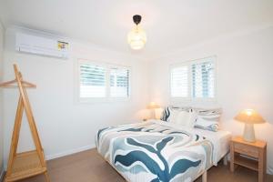 a bedroom with a blue and white bed and windows at Haven at Redcliffe - your stay on the Peninsula in Redcliffe