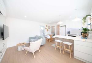 a kitchen and living room with white walls and white furniture at Haven at Redcliffe - your stay on the Peninsula in Redcliffe