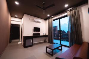 a living room with a couch and a desk with a television at SinQ Village in Bambolim
