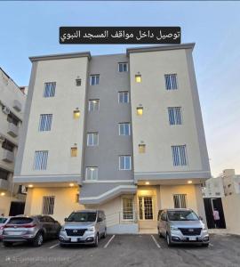a large building with cars parked in a parking lot at شقق جادة قباء in Al Madinah