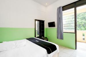 a bedroom with a bed and a green wall at Hotel O Griya Cewang Syariah in Bekasi