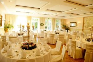 a banquet hall with white tables and white chairs at Bärenkrug in Molfsee