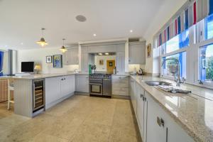 a large kitchen with white cabinets and a large island at Shore View - East Wittering in East Wittering +59 photos