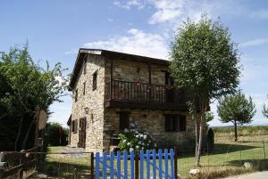una vieja casa de piedra con una valla azul en El Mirador de las Candelas, en Linarejos