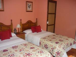 um quarto com 2 camas e almofadas vermelhas em El Mirador de las Candelas em Linarejos