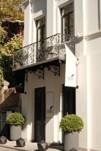 a white building with a balcony and two plants at STROFI Boutique Hotel in Tbilisi City