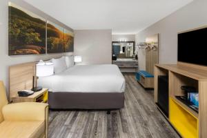 a hotel room with a bed and a flat screen tv at Days Inn by Wyndham Branson Ozarks in Branson