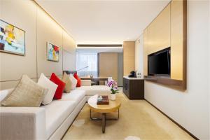 Una sala de estar con un sofá blanco y un televisor. en Grand Metropark Hotel Beijing, en Beijing
