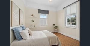 a white bedroom with a bed and two windows at Parkside Family Haven - 5bdrm in Brisbane +16 photos