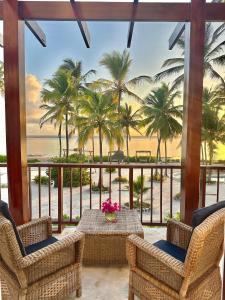 a balcony with a table and chairs and palm trees at Beach Front Villa Ocean View Zanzibar in Pongwe