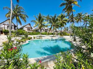a swimming pool at a resort with palm trees at Beach Front Villa Ocean View Zanzibar in Pongwe