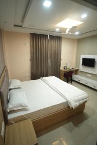 a bedroom with a bed and a desk and a television at Aroma Homes in North Lakhimpur
