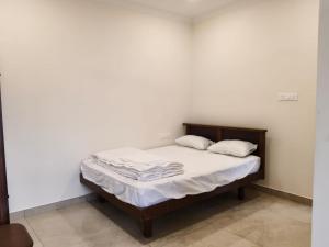 a bedroom with a bed with white sheets and pillows at Jayanthi Mahal in Tiruchirappalli