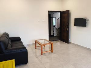a living room with a black couch and a table at Jayanthi Mahal in Tiruchirappalli