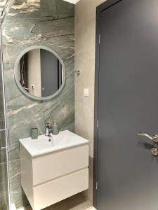 een badkamer met een witte wastafel en een spiegel bij Apartment Voulas 3 in Ptolemaida