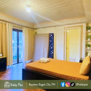 ein Schlafzimmer mit einem Bett mit einer orangefarbenen Tagesdecke in der Unterkunft City View 2BR Home in Burnham - Dalisay Unit by Balay Paz in Baguio City