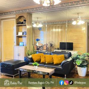 ein Wohnzimmer mit einem schwarzen Ledersofa und gelben Kissen in der Unterkunft City View 2BR Home in Burnham - Dalisay Unit by Balay Paz in Baguio City