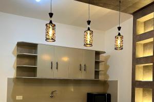 Una cocina con tres luces colgando del techo. en Refugio del Mar, en Manta