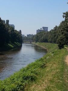 a river with a bridge in the background and buildings at Apartman Vills in Sarajevo
