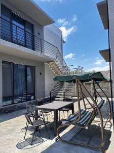 un patio avec une table, des chaises et un parasol dans l'établissement Riverside Cotagge, à Poti