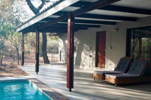 a patio with chairs and a swimming pool at Nzenga Lodge in Hoedspruit