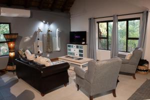 a living room with a couch and chairs and a tv at Nzenga Lodge in Hoedspruit
