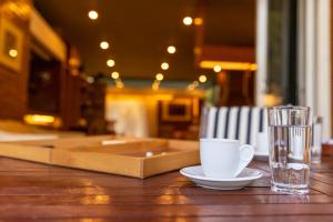 a cup and a glass sitting on a wooden table at Retro House in Rafina
