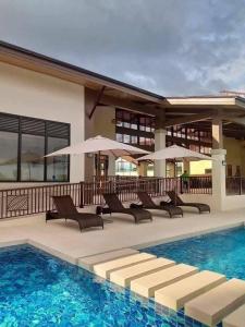 a pool with chairs and umbrellas next to a building at Azure Edge in Dauis