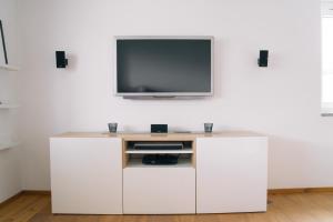 um centro de entretenimento branco com uma televisão na parede em Relax in Thaur em Thaur