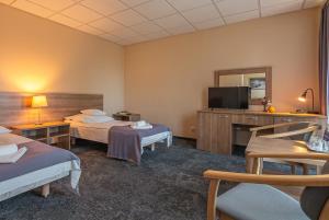 a hotel room with two beds and a television at Hotel Olimpijski in Oświęcim