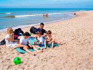 a group of people sitting on the beach at 4 person holiday home in Ringkøbing-By Traum in Ringkøbing