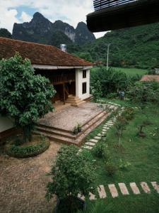 une petite maison avec des montagnes en arrière-plan dans l'établissement Là Nhà Homestay, à Hữu Lũng