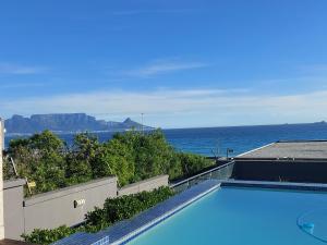 una piscina con el océano al fondo en Infinity Beachfront 607 - Self Catering Unit, en Bloubergstrand
